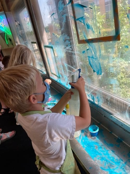 A young boy paints a window blue as part of an exhibit at the Madison Children's Museum.