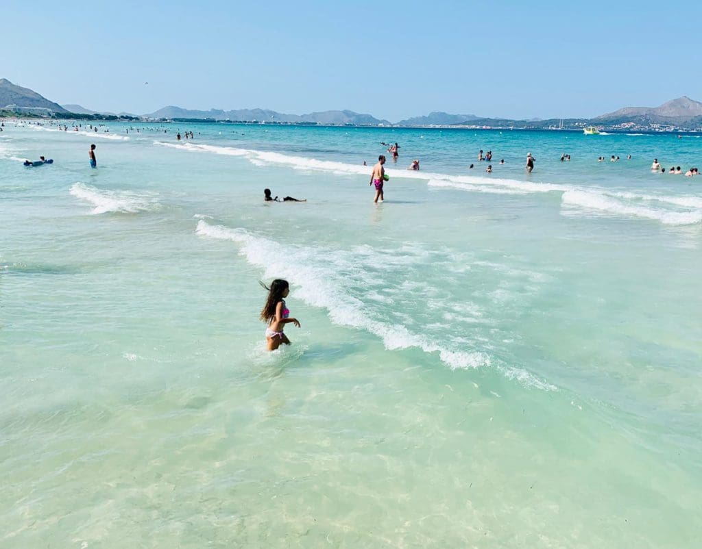 People walk along the waves of the water off-shore from Mallorca.