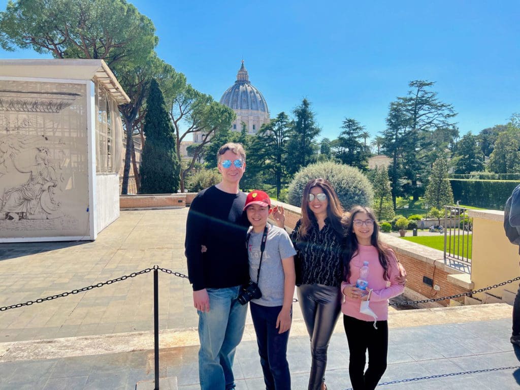 A family of four stands together while exploring Rome on a sunny day.