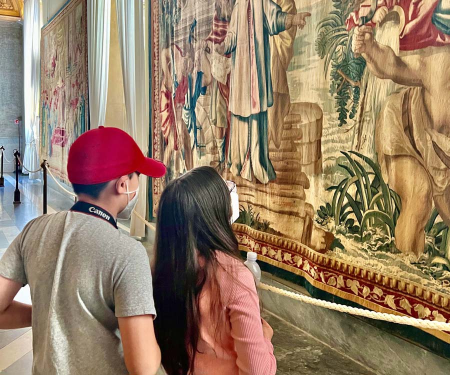 Two kids stand together and admire a painting, while exploring a museum.