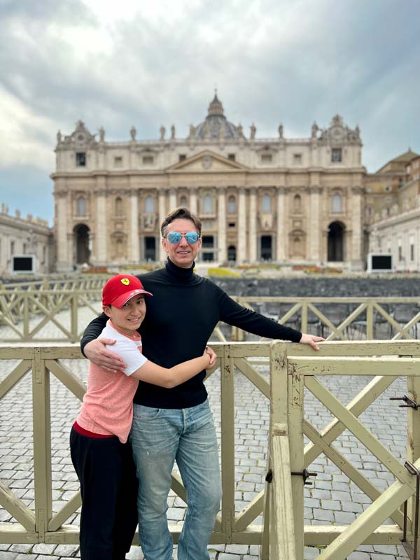 A young boy and his dad stand together in front of Rome's St. Peter's Basilica, a must stop on our Rome itinerary with kids.