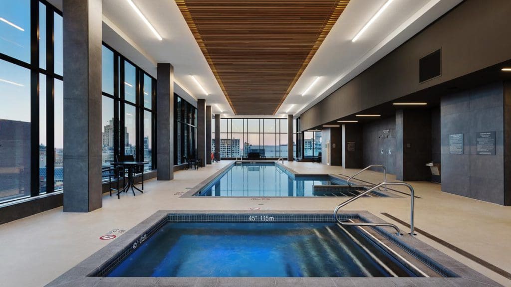 The indoor pool and whirl pool, with full windows on one side with a view of downtown, at .AC Hotel by Marriott Montreal Downtown.