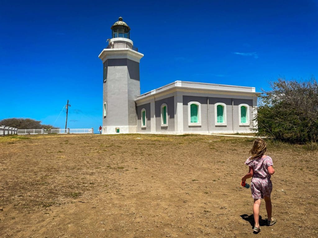 A young girl walks around the grounds of Cabo Rojo National Wildlife Refuge, with the lighthouse in the distance, a must stop on any Puerto Rico itinerary for families.