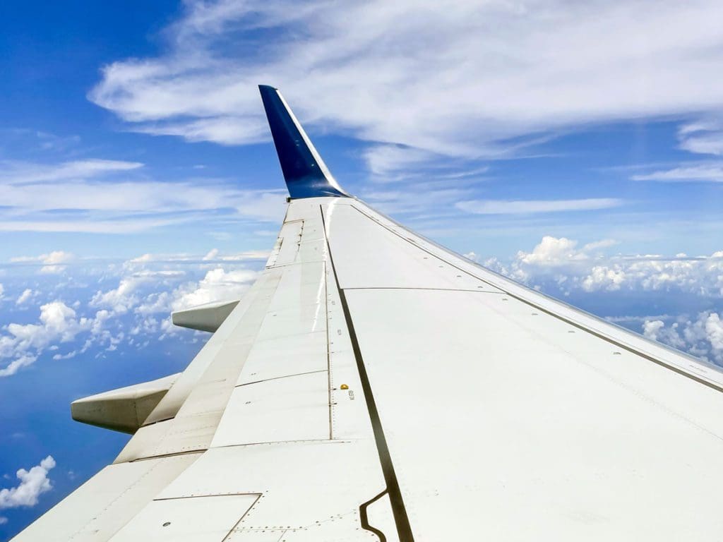 The wing of a Delta airplane extends into the sky.