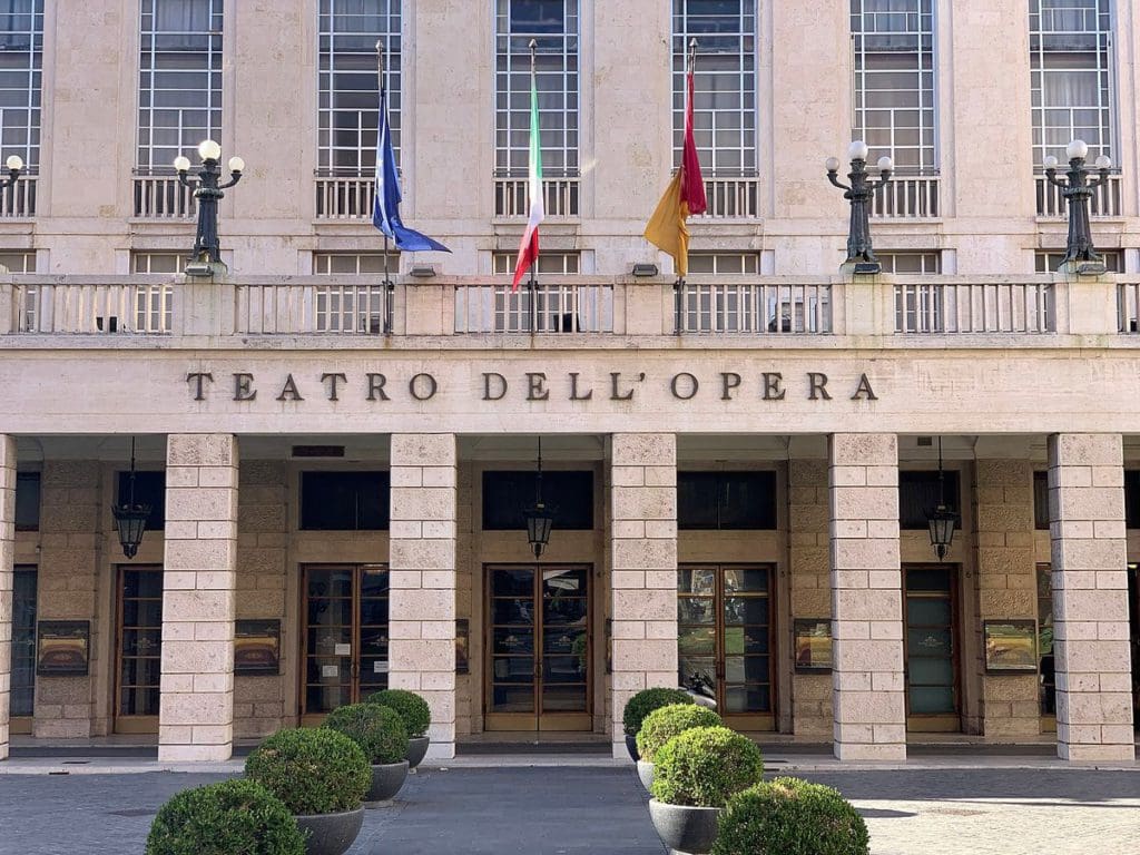 The columned entrance to Teatro Dell’Opera with flags waving overhead.
