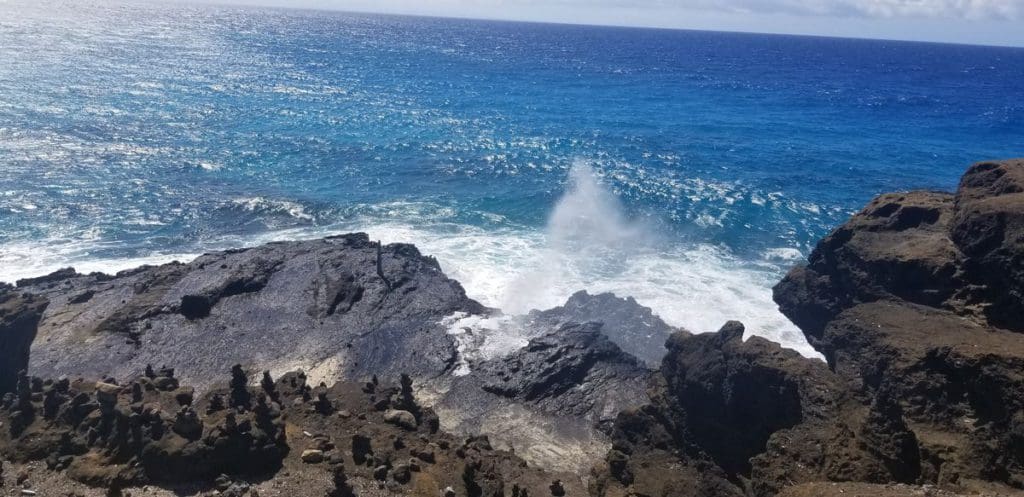 The Halona Blowhole shooting water into the air on a clear blue day, one of the best things to do in Oahu with kids.