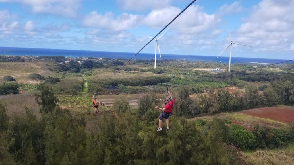 A dad and his teen daughter zipline across the lines at Keana Farms, one of the best things to do in Oahu with kids.