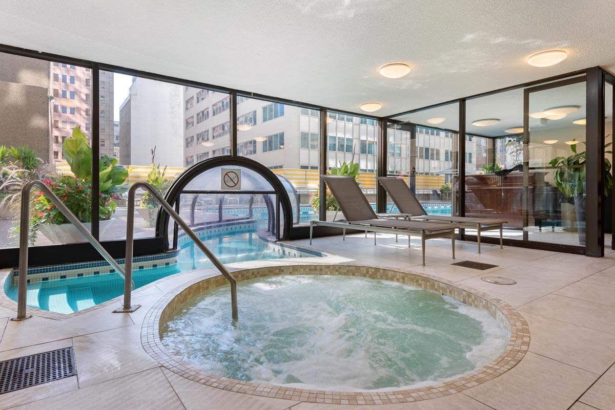 The indoor pool and whirl pool at The Omni Mont-Royal Hotel, with floor to ceiling glass windows and a view of downtown.