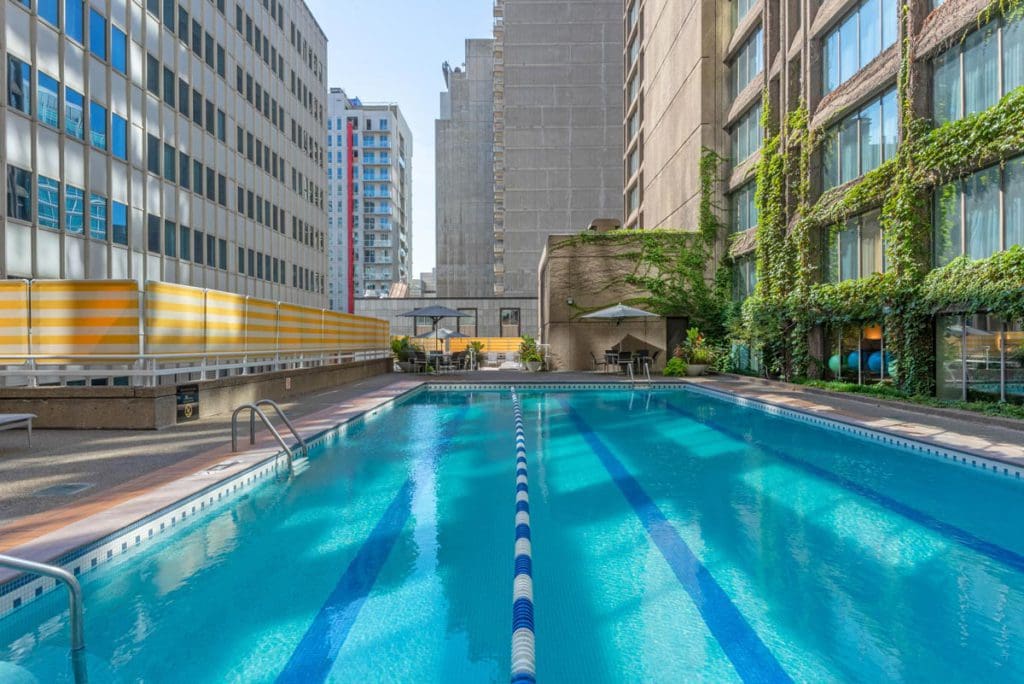 The outdoor pool at The Omni Mont-Royal Hotel, surrounded by downtown buildings, on a sunny day.