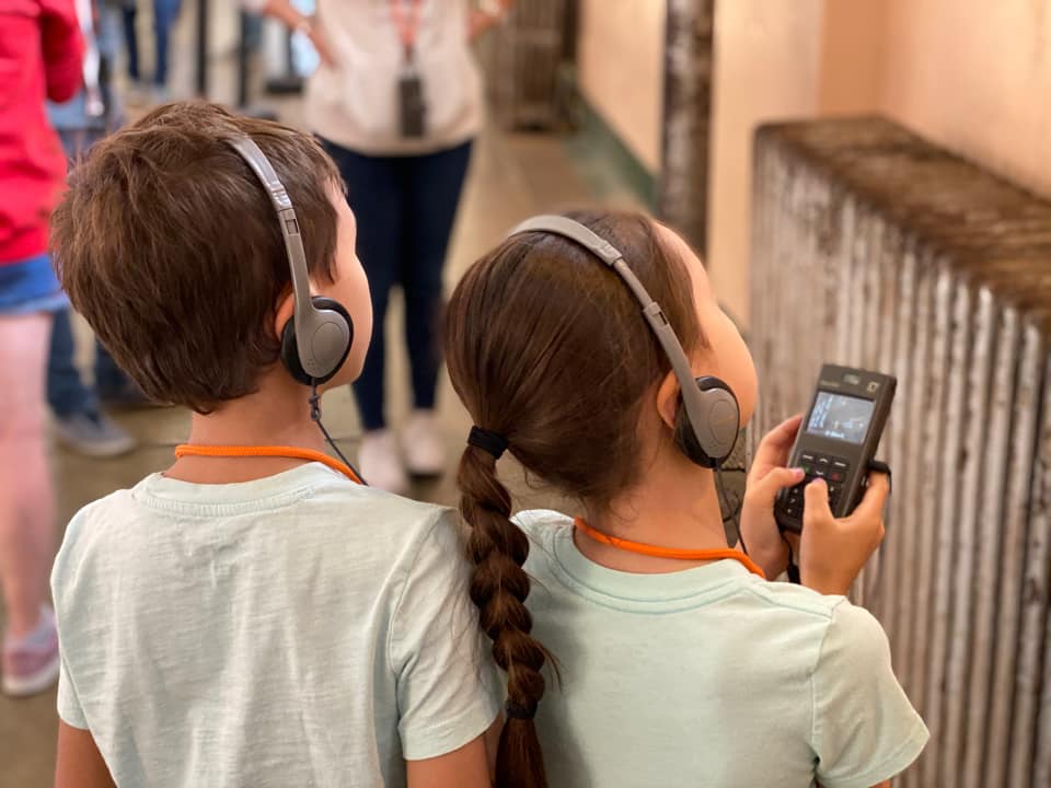 Two kids listen to an audio tour while exploring Alcatraz together.