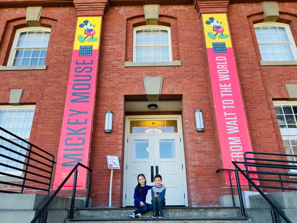 Two kids stand outside the entrance to The Walt Disney Family Museum.