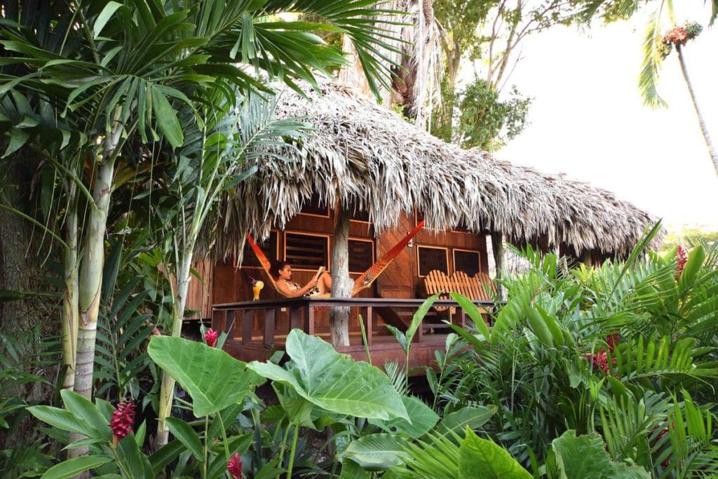 A woman sits in a hammock on the balcony of her villa at Lamanai Outpost Lodge.