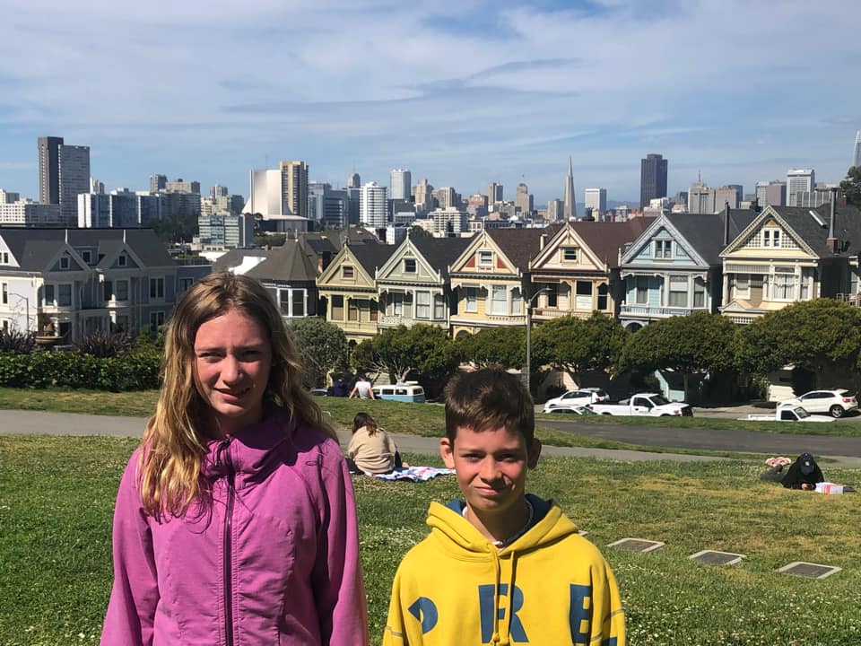 Two kids stand in the park across from the Painted Ladies, colorful houses, one of the best things to do in San Francisco with kids.