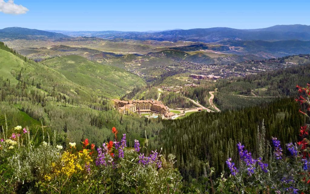 A beautiful aerial view of Montage Deer Valley during the spring time, when the hotel is surrounded by verdant plants and blooming wildflowers at one of the best eco-friendly hotels in the United States for families.