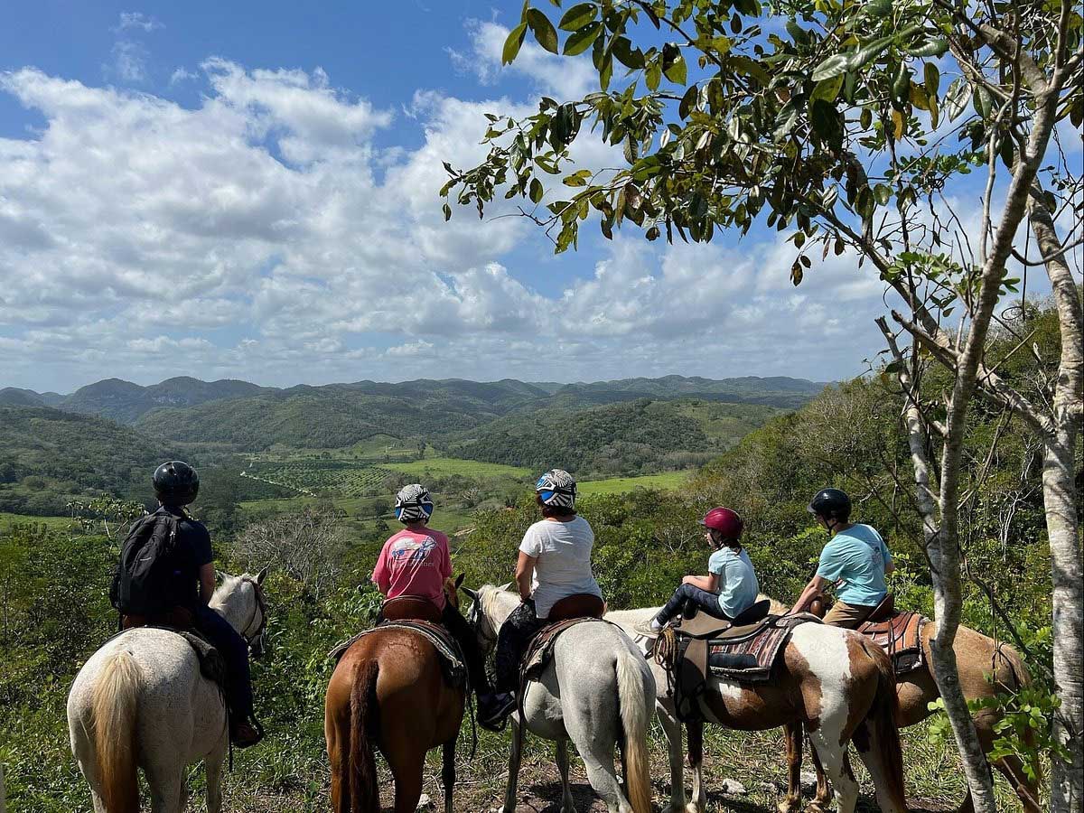 Five people on horseback enjoyed a guided tour through Mystic River Resort, one of the best Belize resorts for a family vacation.