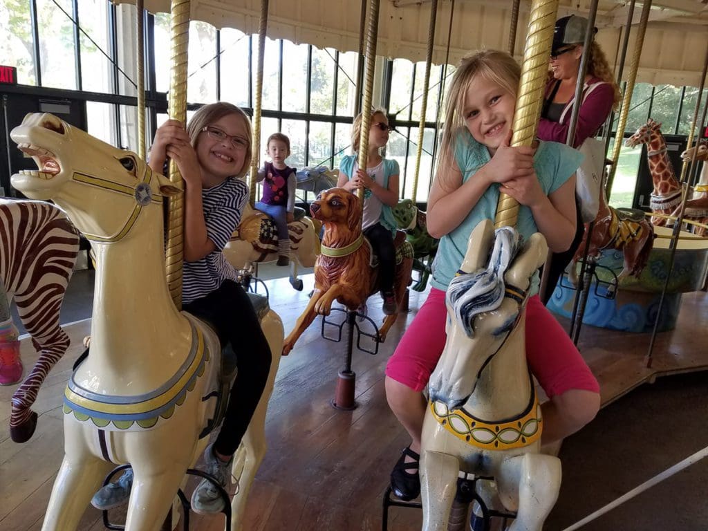 Two girls smile as they ride a carousel together in Golden Gate Park.