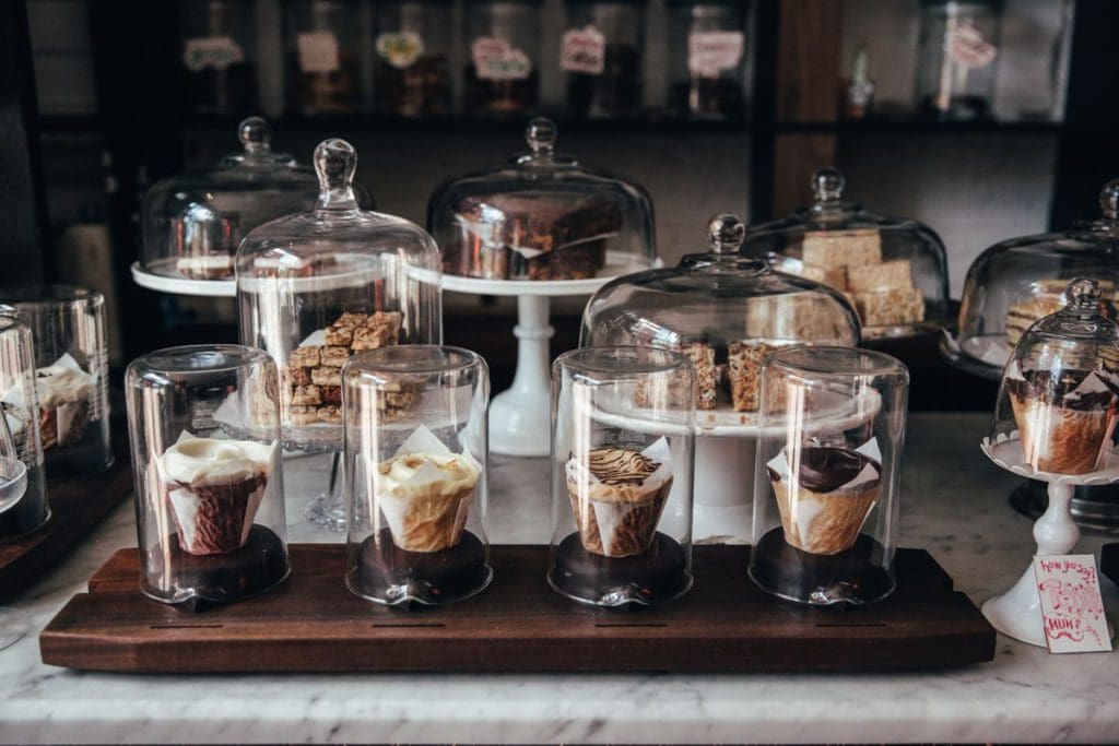 A counter filled with sweets in charming cases at Baked and Wired, including cupcakes and cakes.