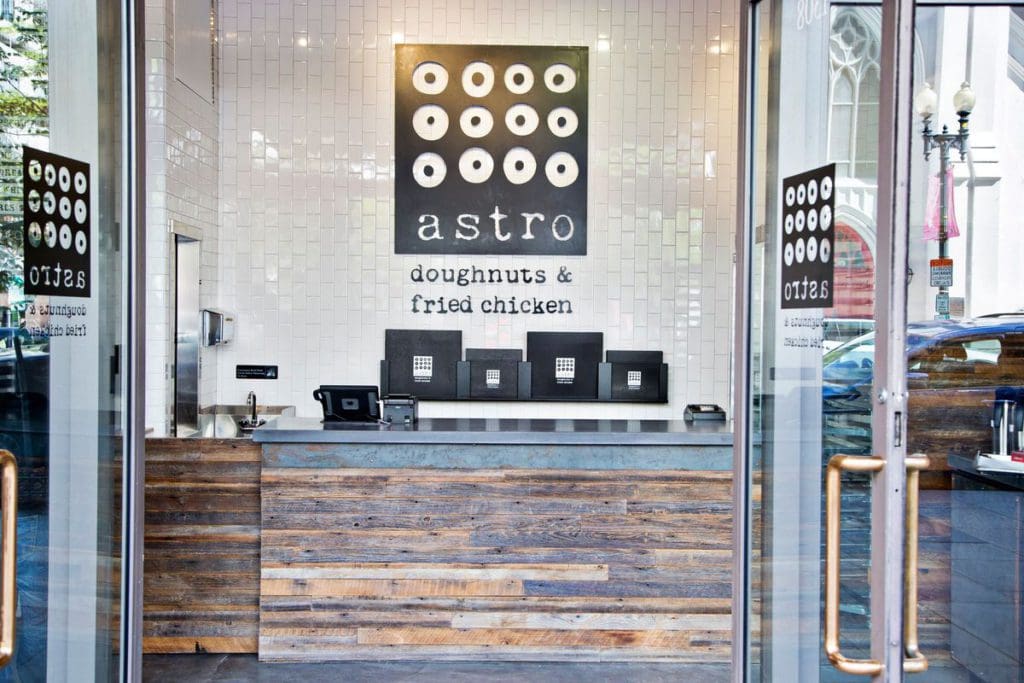 The entrance to Astro Doughnuts and Fried Chicken, featuring a trendy white interior with black lettering at one of the best dessert spots in DC for families.