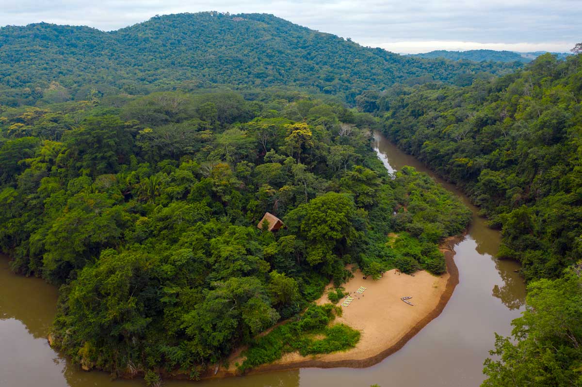 An aerial view of the grounds of Sweet Songs Jungle Lodge, a Muy’Ono Resort nestled along a river.