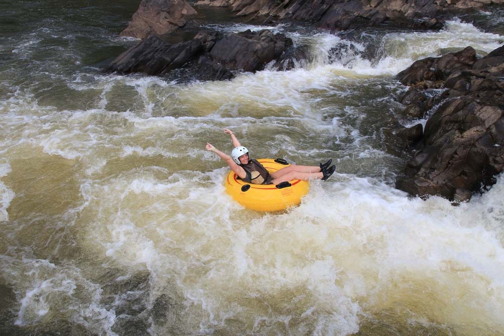 A woman tubes down a rushing river through a guided tour from Black Rock Lodge, one of the best Belize resorts for a family vacation.