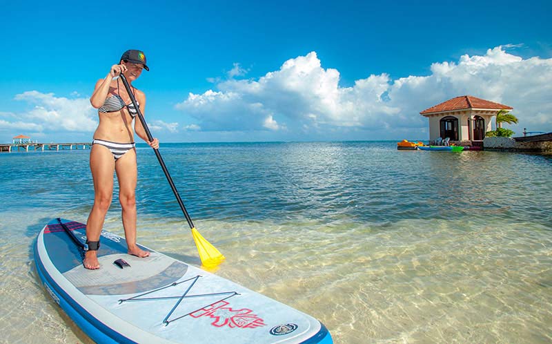 A woman paddles along on a stand-up paddle-board on the ocean near the shore of Coco Beach Resort.