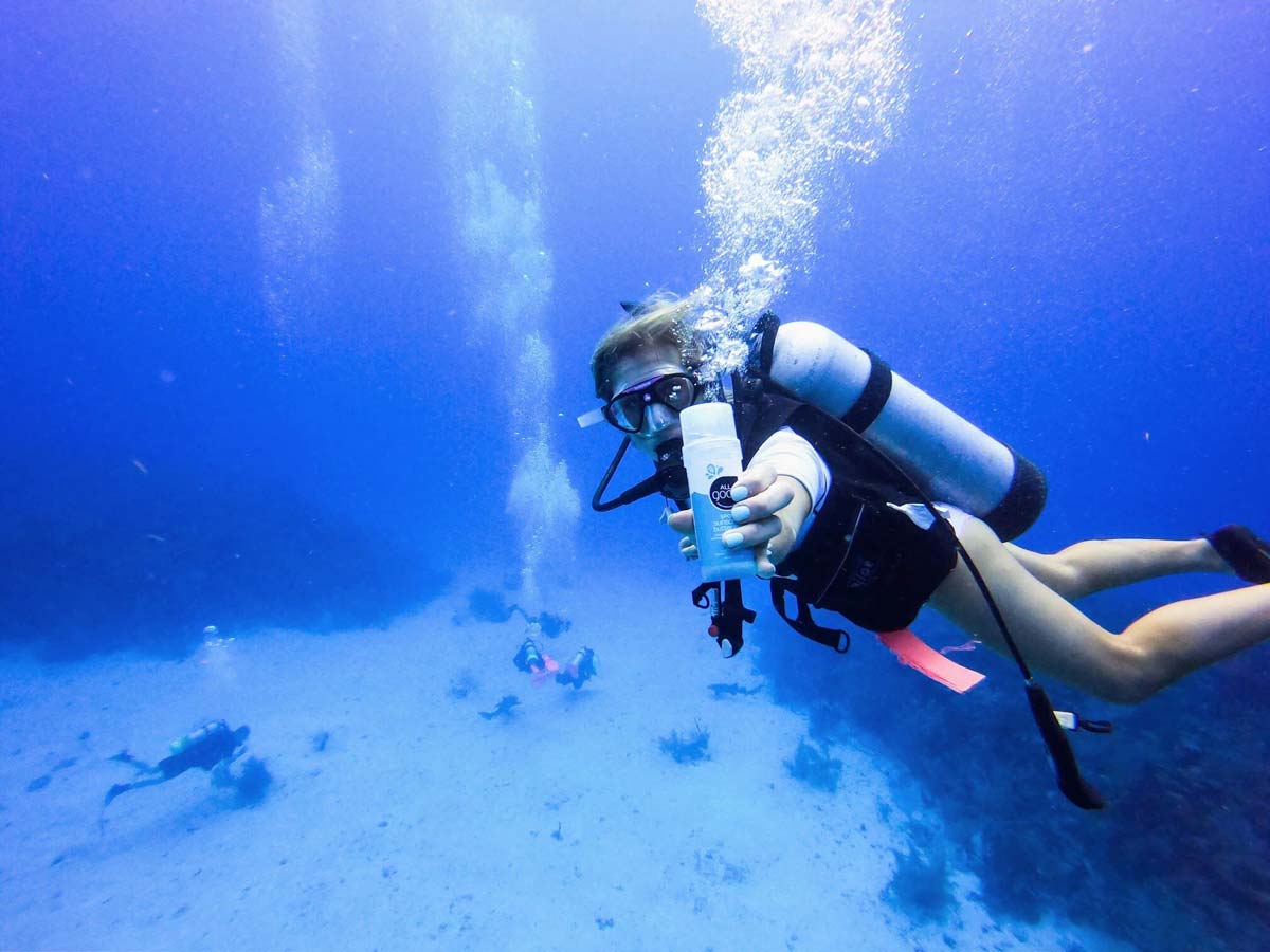 A woman scuba dives off-shore from Hamanasi Adventure & Dive Resort, one of the best Belize resorts for a family vacation.