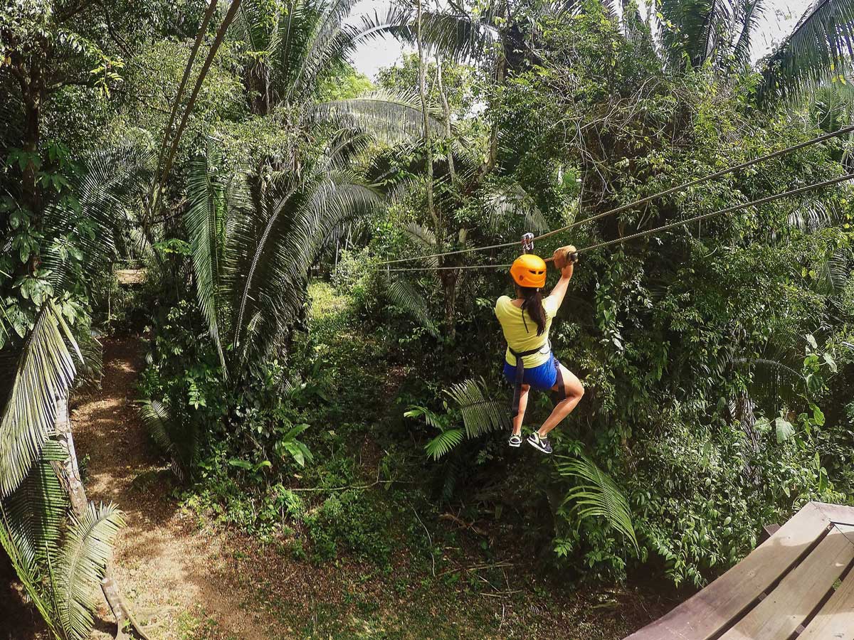 A young woman ziplines through the rainforest while touring with Ka'ana Resort, one of the best Belize resorts for a family vacation.