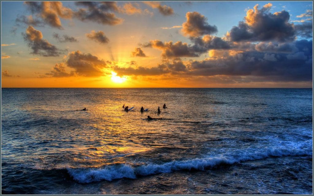 A bright sunset over swimmers enjoying an end of day swim off-shore from Turtle Bay Beach.
