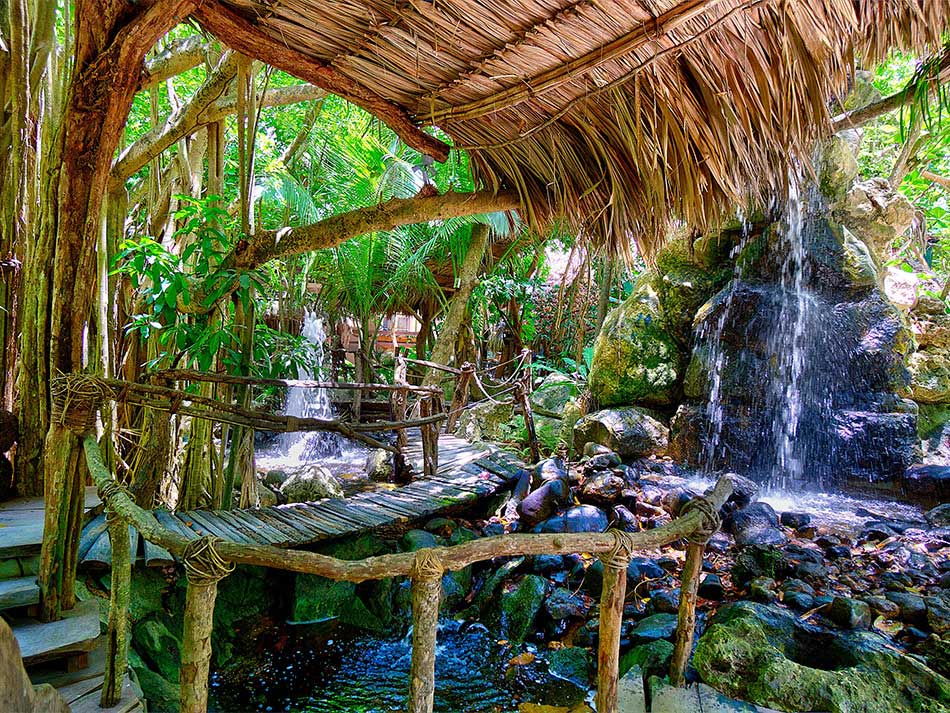 Inside the winding, wooded path of Xanadu Island Resort, featuring a waterfall and lush foliage.
