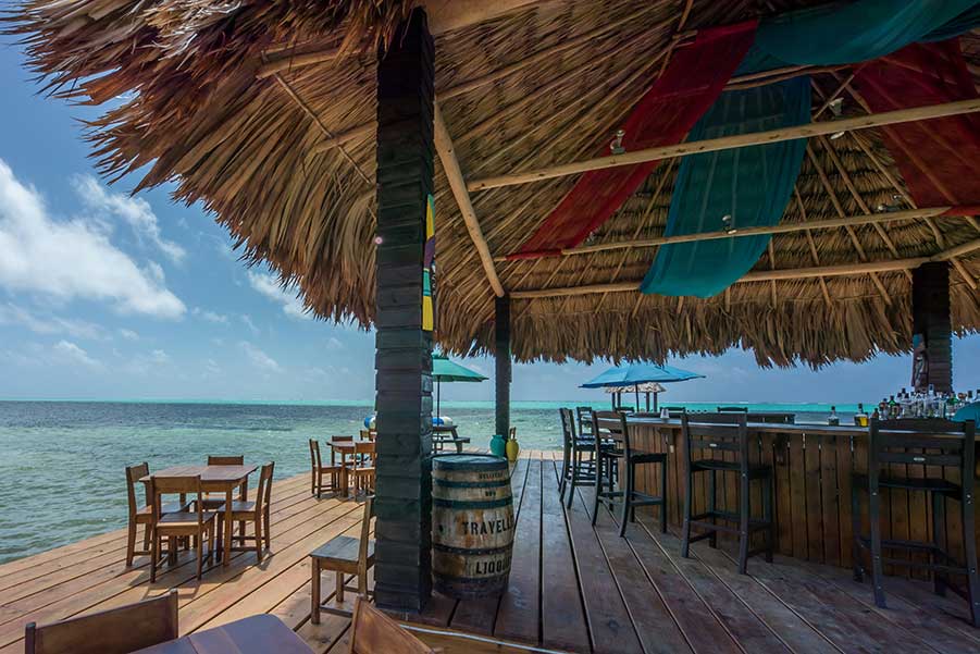 Inside the ocean-side bar area of X’Tan Ha Resort, with tables featuring an ocean view.