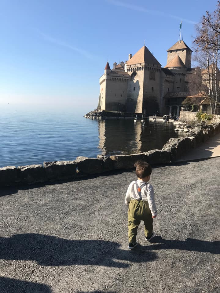 A young boy toddles past a castle near Montreux.