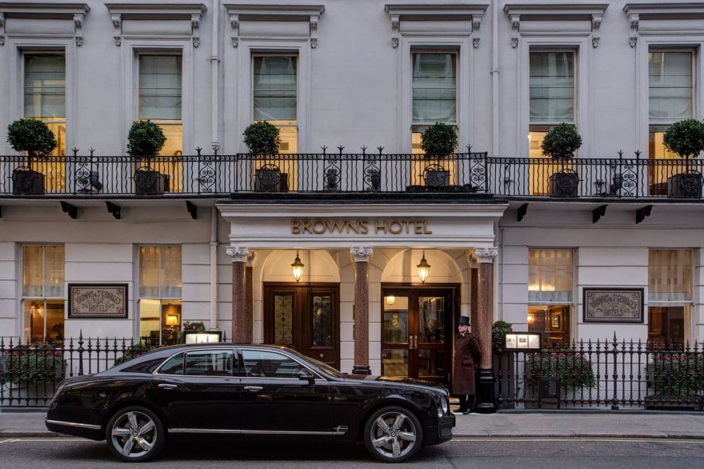 A black car parked outside the entrance to Brown's Hotel, a Rocco Forte Hotel, lit up at night.