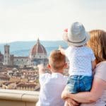 A mom and her two kids look out onto a Florence skyline, while one young one boy points at the Duomo.