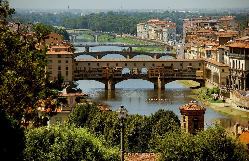 A view of Ponte Vecchio through the trees from a distance.
