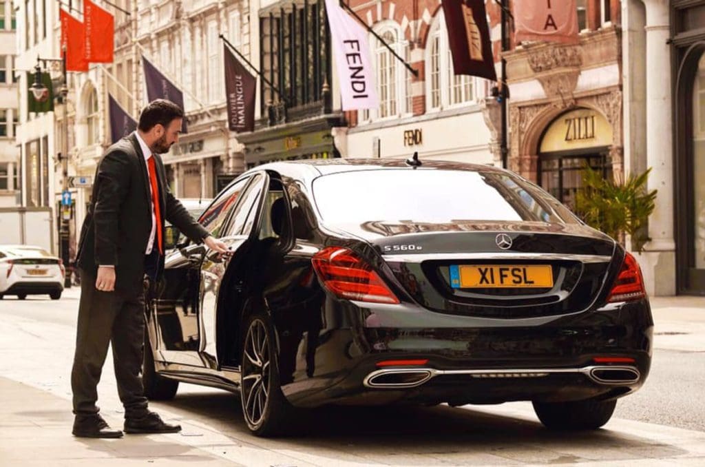 A staff member opens a car door outside the entrance to Four Seasons Hotel London at Park Lane.
