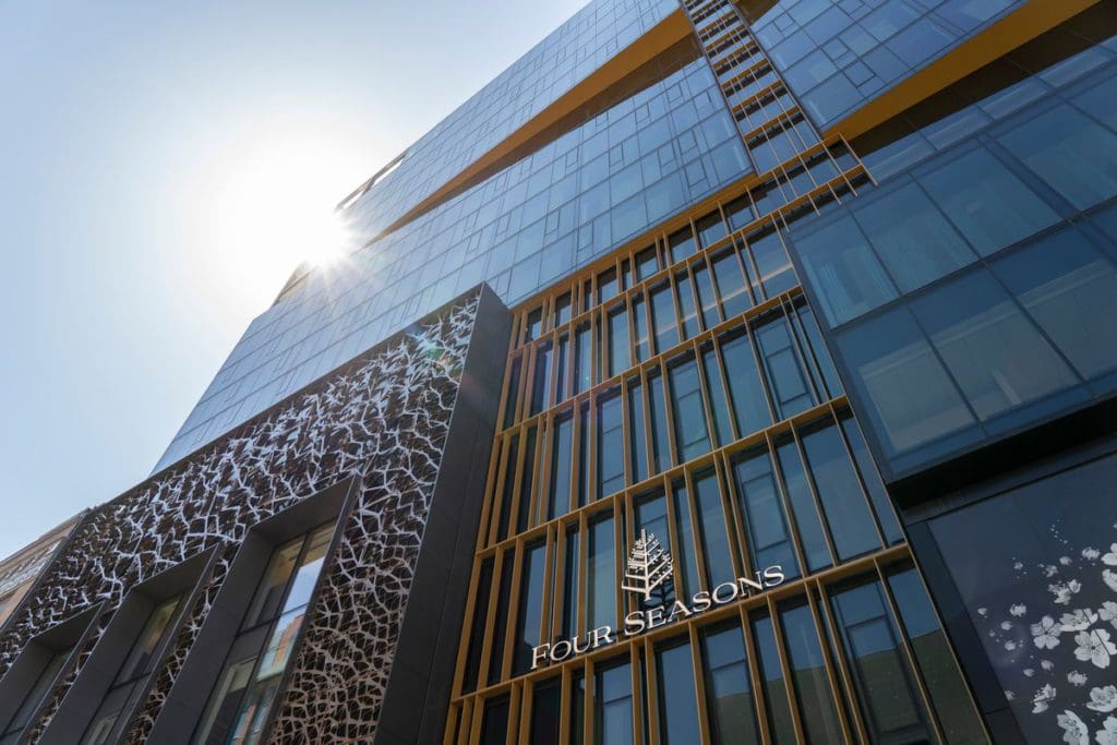 The exterior of Four Seasons Hotel Montreal, with an angle upward to see the top of the building and sky.