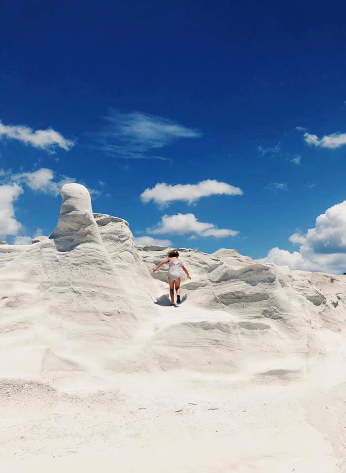 A young girl climbs along rock formations on the island of Milos, one of the best Greek islands for families.