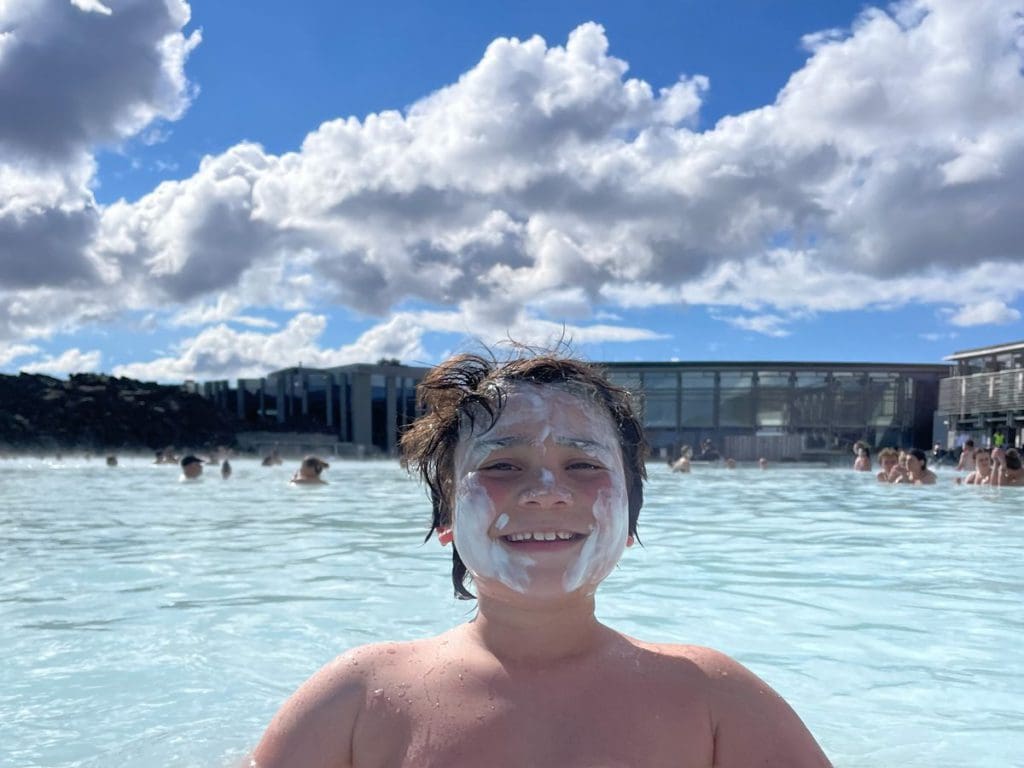 A young boy enjoys a dip in the Blue Lagoon, the final stop on this Iceland itinerary for families.