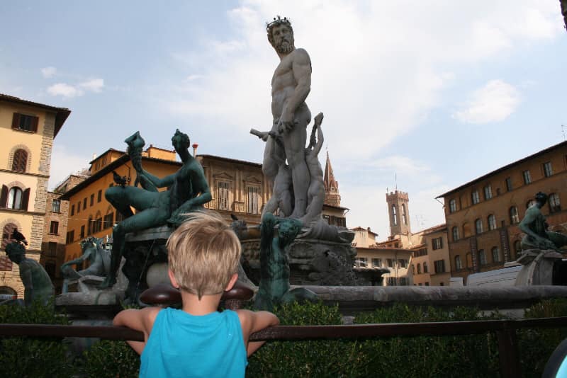 A young boy looks at the large central statue within Piazza della Signoria, one of the best places to visit on a Florence itinerary for families. 