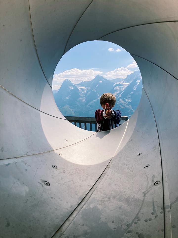 A boy gives a thumbs up through a tunnel, while hiking near Murren.