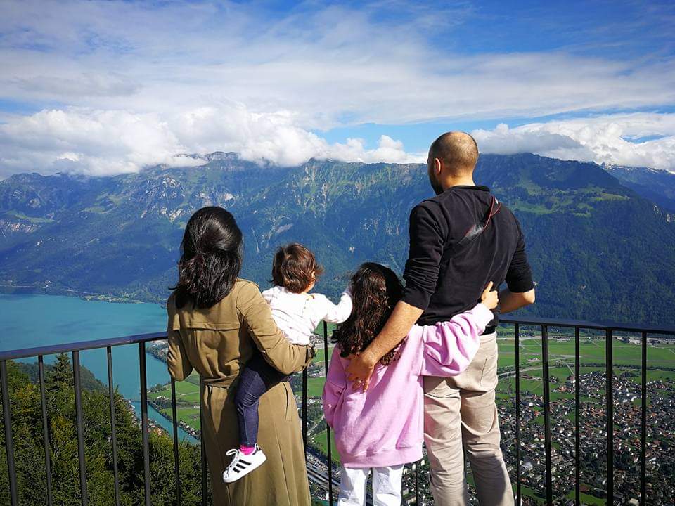 A family of four stands together looking out onto a view of Harder Kulm in Switzerland.
