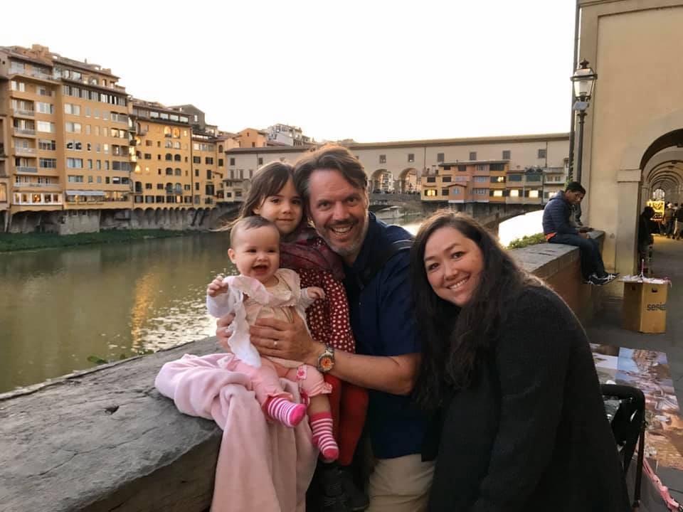 A family of four poses in front of Ponte Vecchio in Florence.