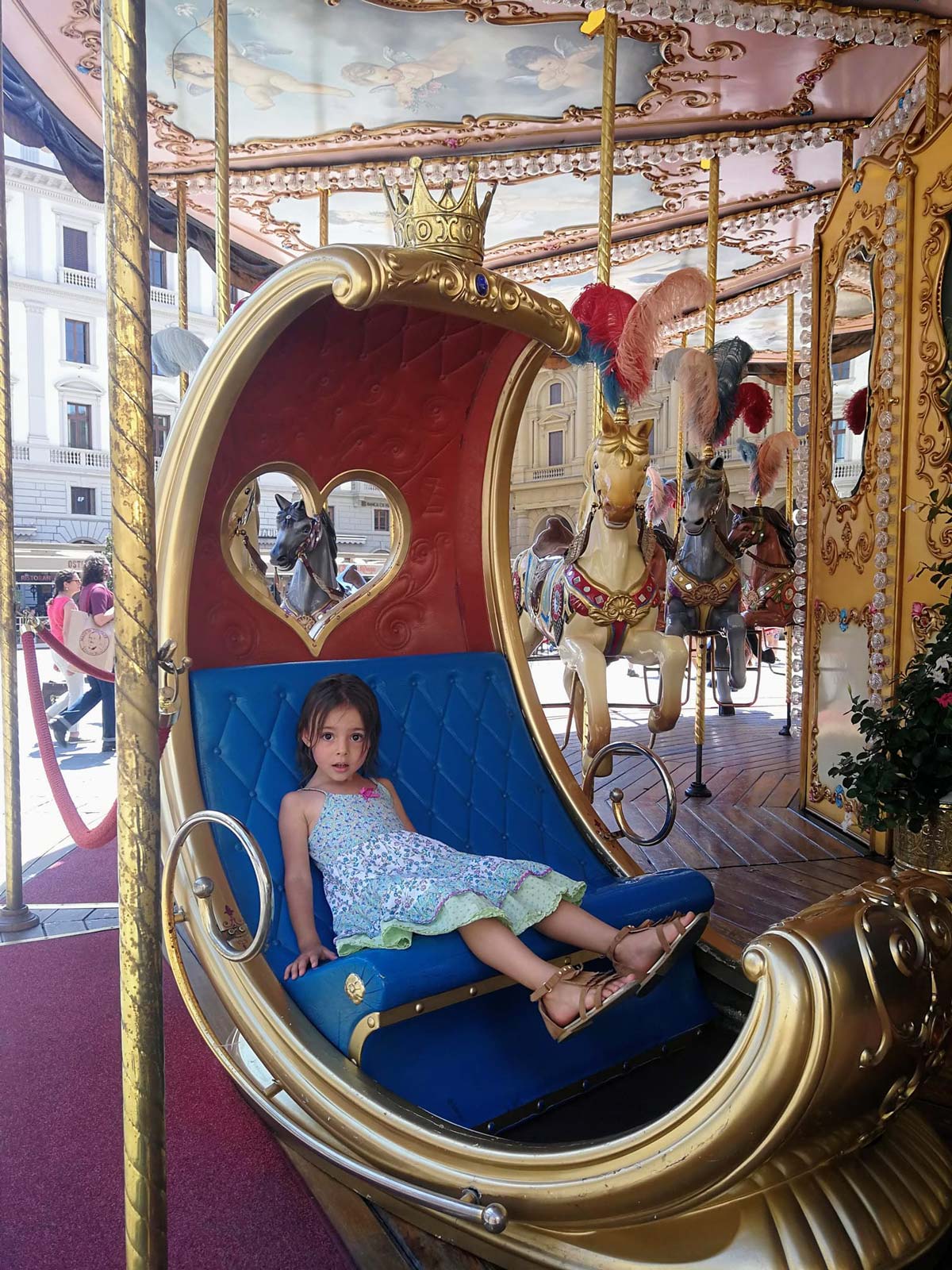 A young girl sits in a carousel seat in Piazza della Repubblica.