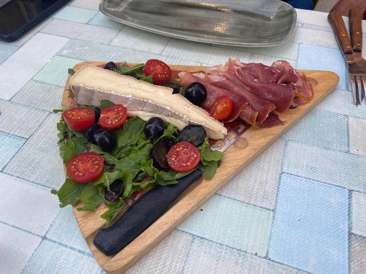 A cheeseboard with fresh cheese and vegetables, enjoying the great food is one of our best tips for visiting Malta with kids.