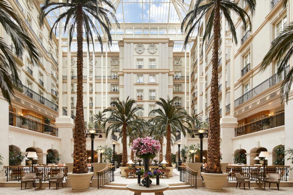 The indoor atrium at The Landmark London, featuring lush greenery and an open and airy feel.