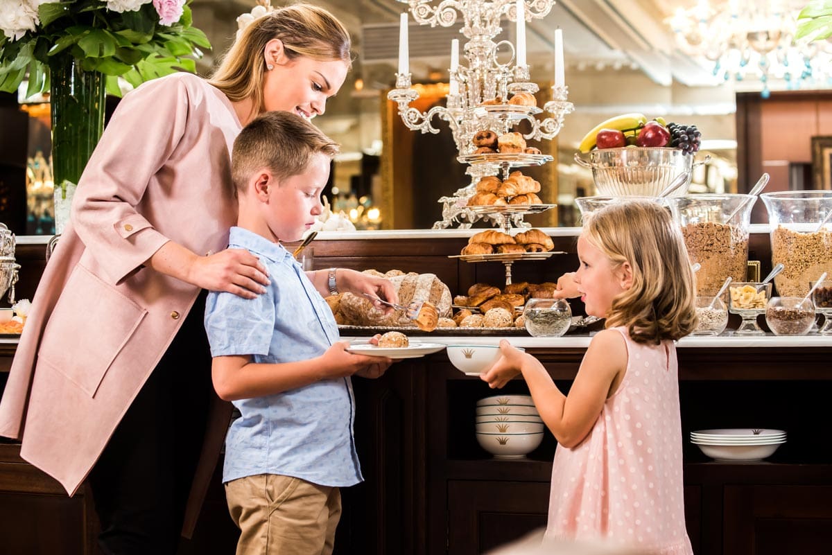 A mom and her two young children enjoy a selection of sweets during Tea Time at The Rubens at the Palace.