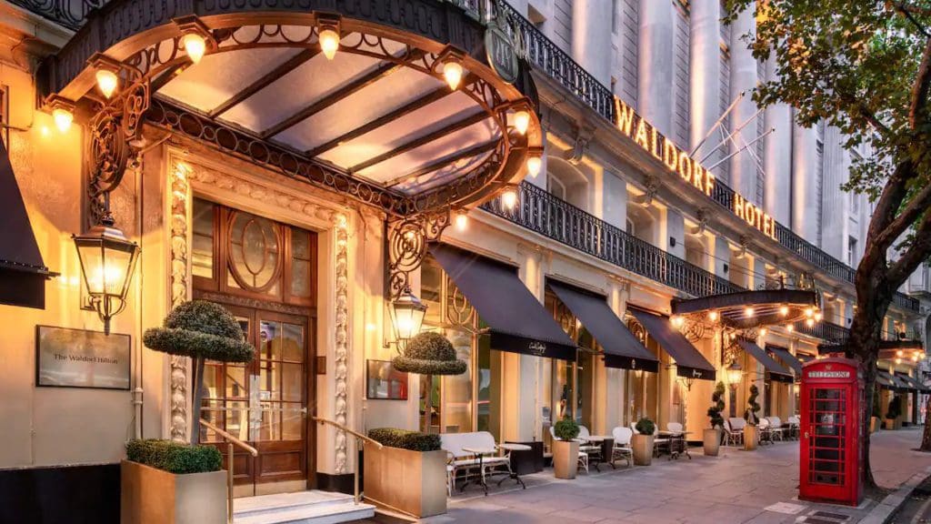 The exterior entrance to The Waldorf Hilton, London lit up at night.