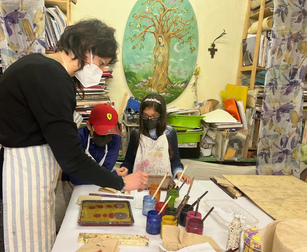 Two kids, with an instructor, learn to make marble art while in Florence.