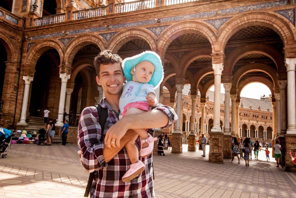 A dad holds his infant daughter as they explore a historic sight in Seville.