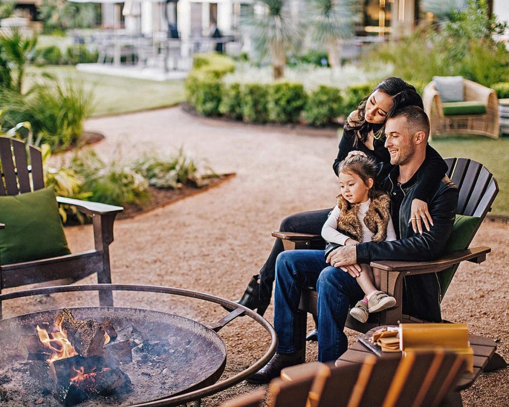 A family of three snuggles together, while enjoy a bon fire at Four Seasons Hotel Austin.